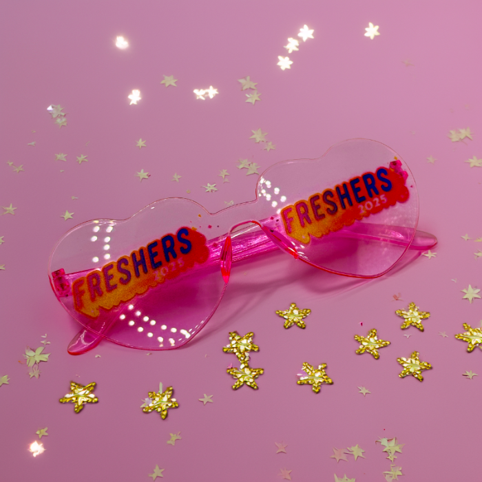 Pink sunglasses with 'FRESHERS 2023' text on a pink background with gold stars.